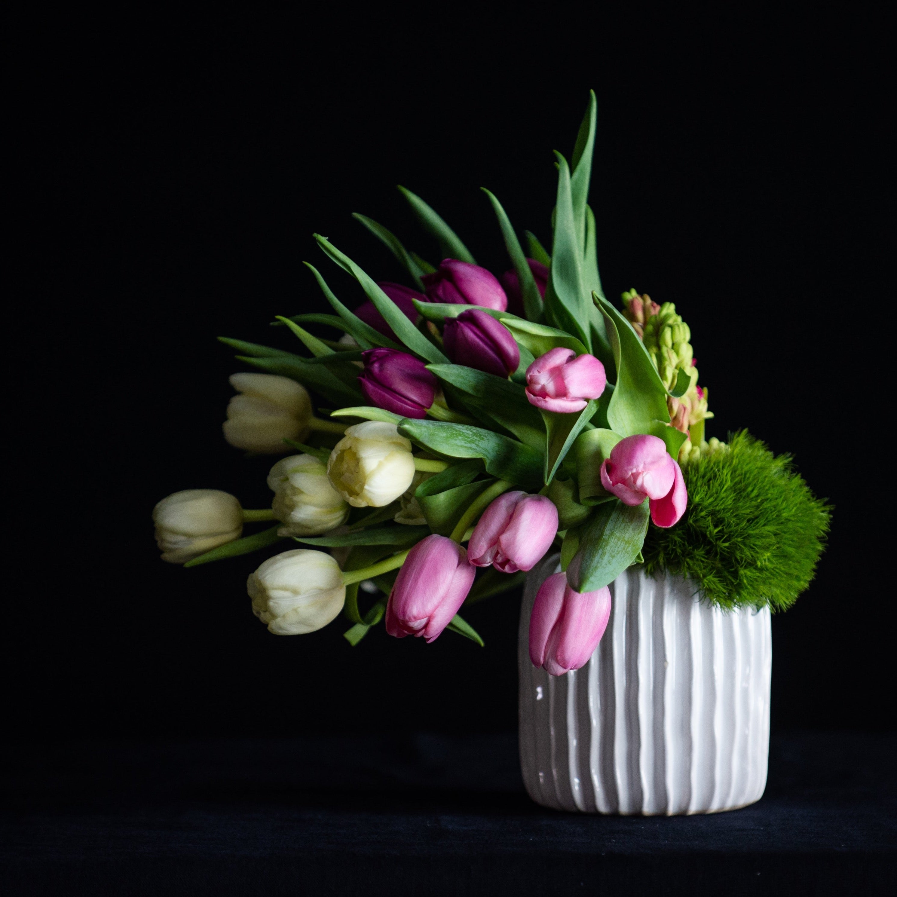 Mother's Day floral arrangement of tulips and hyacinth in pastel colors. In a white ceramic vase