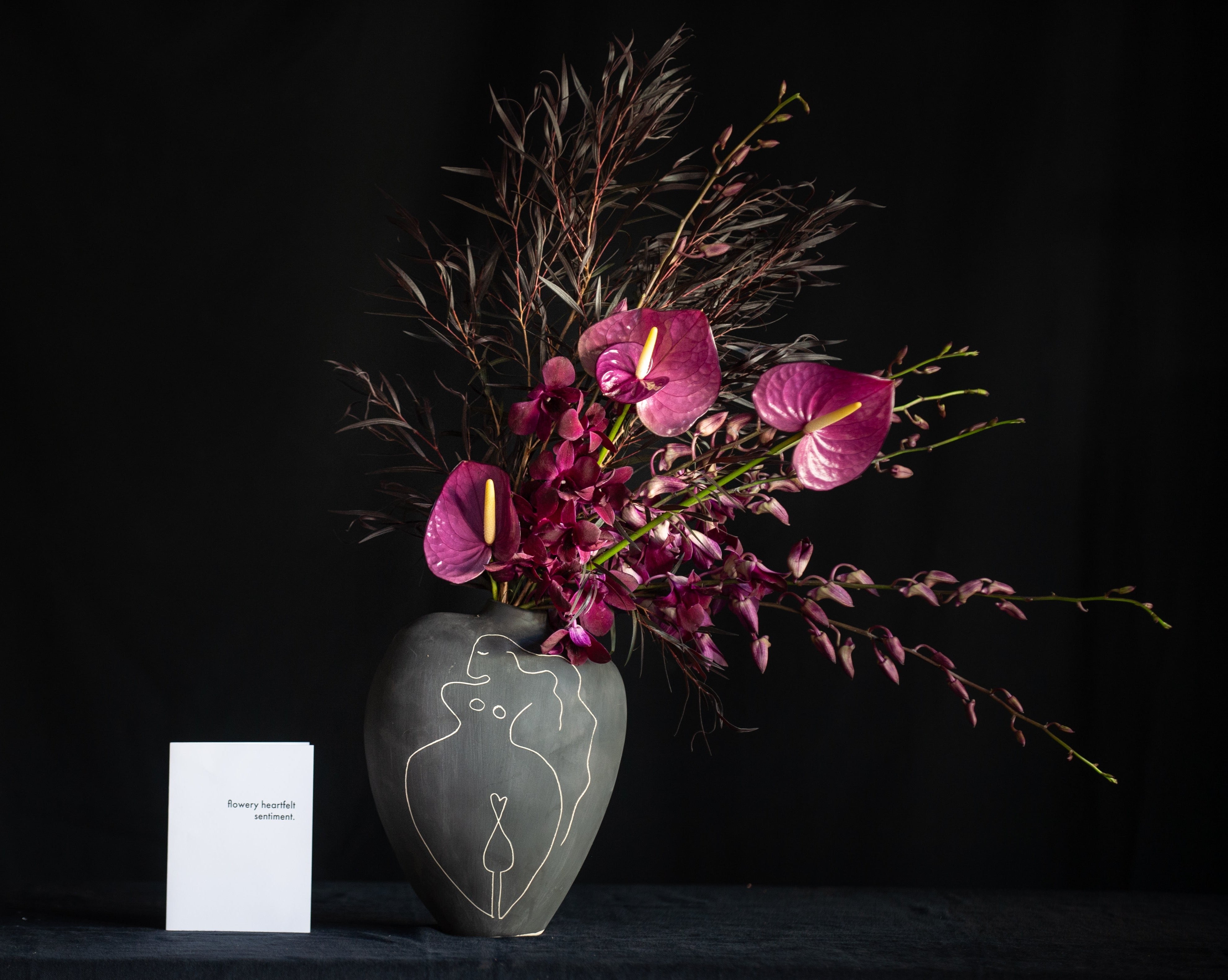 An artistic female vase filled with orchids and anthurium for Valentine's Day