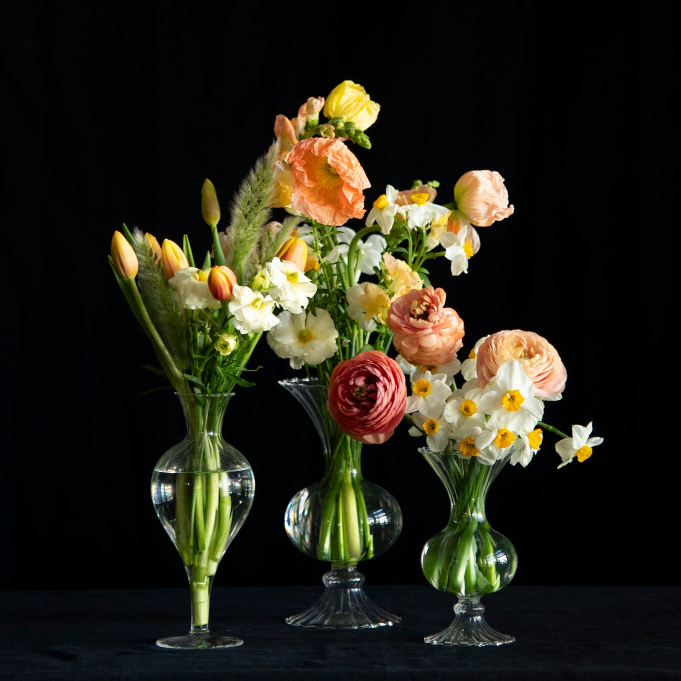 trio of glass vases filled with seasonal flowers