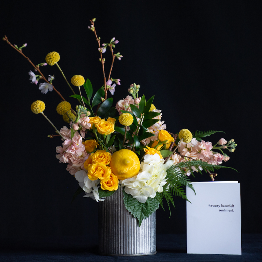 Spring floral design of yellow and pastel stems with a lemon accent. Created by a local florist. 