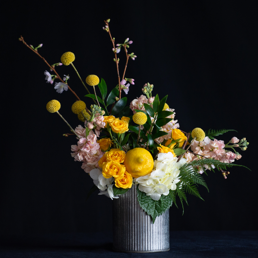Spring floral design of yellow and pastel flowers with a lemon accent. Local florist. 