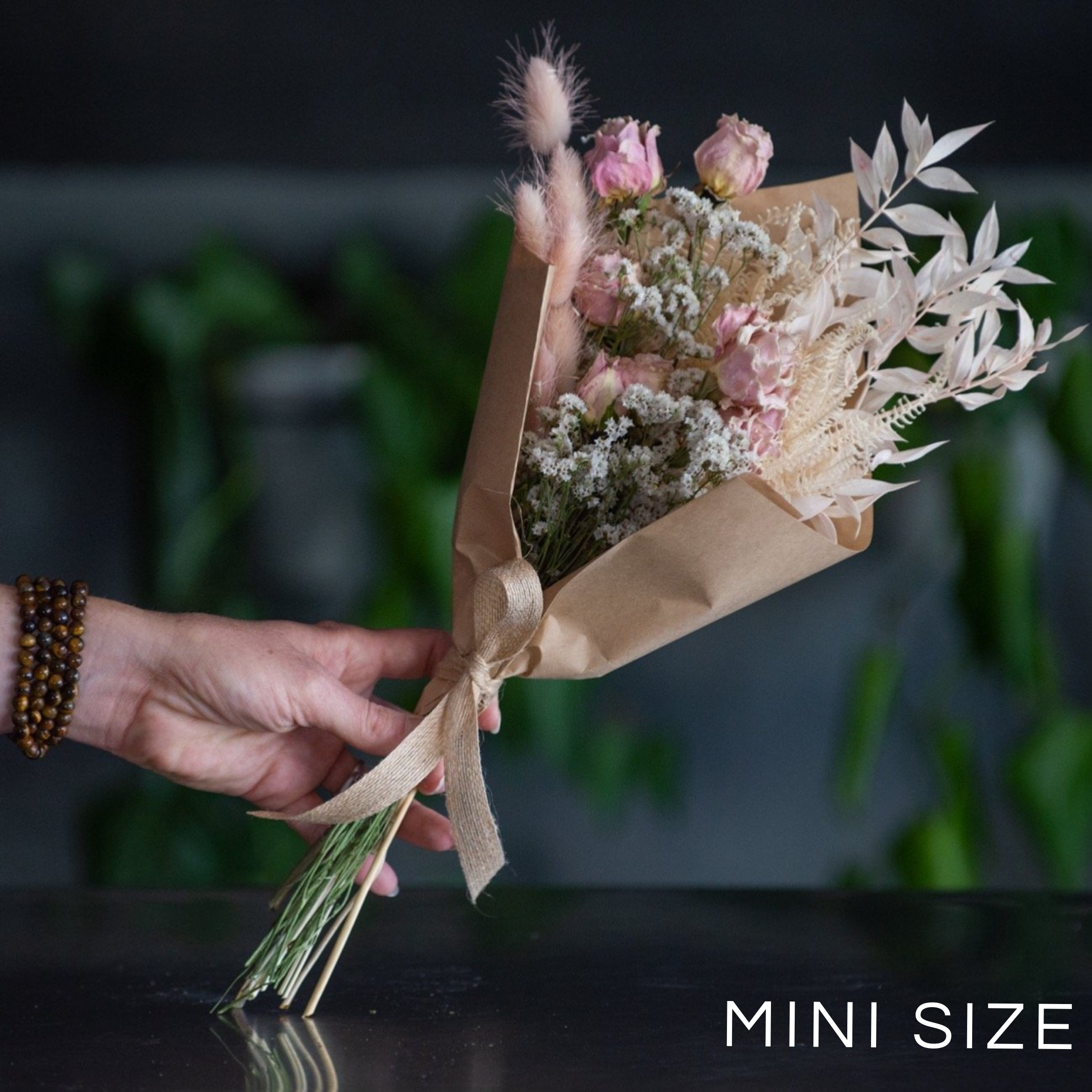A small hand tied bouquet of dried and preserved flowers. Wrapped in a craft wrap.