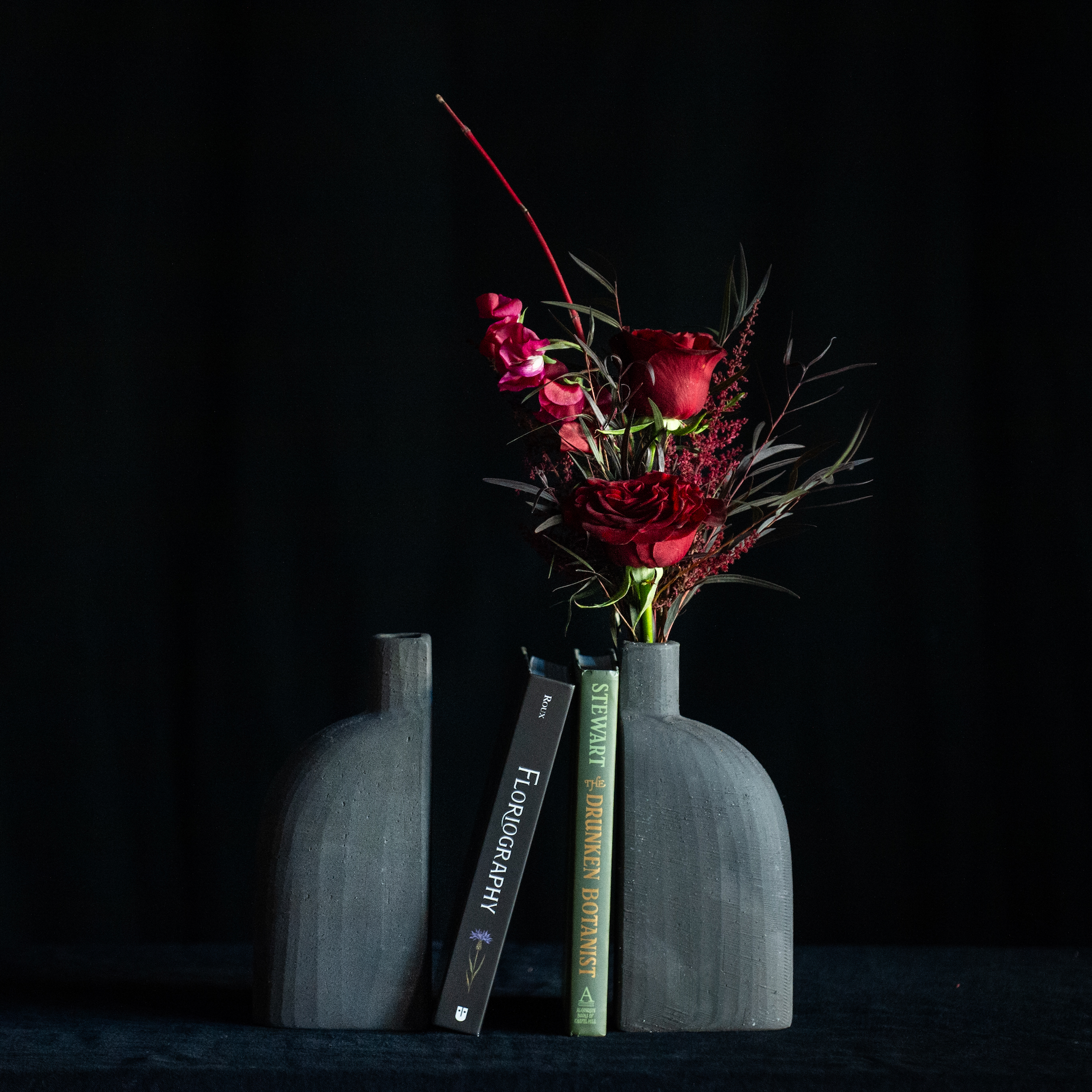 Black bud vase bookends filled with red roses and premium accents