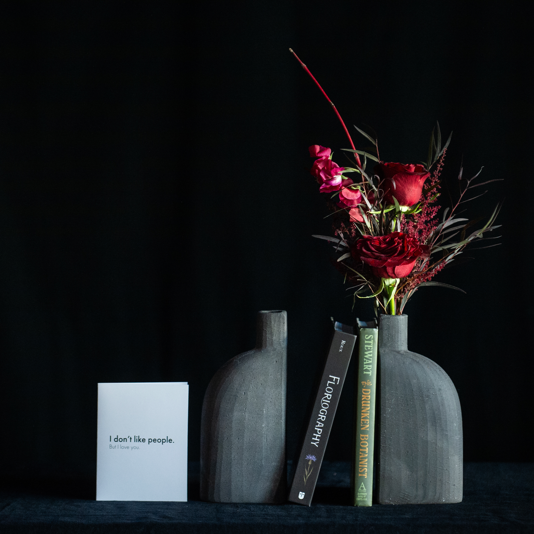 Black bookend bud vase filled with red roses and accents