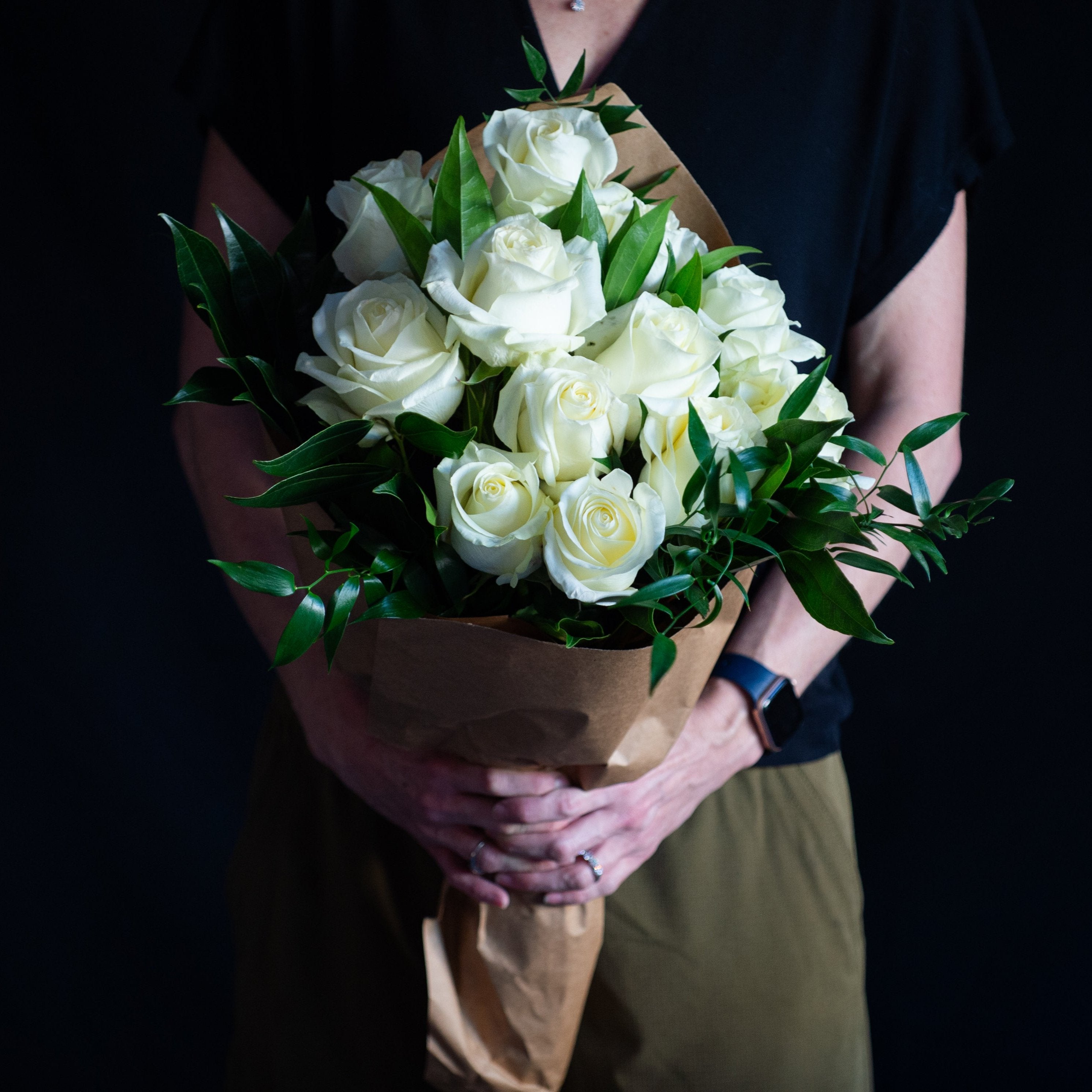 dozen white roses with holiday greens