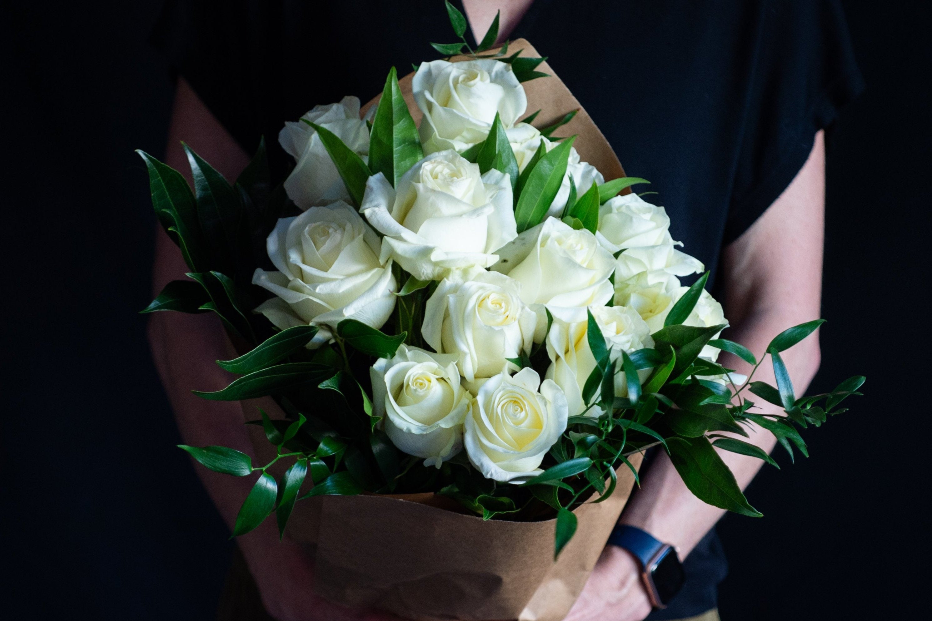 dozen white roses with holiday greens