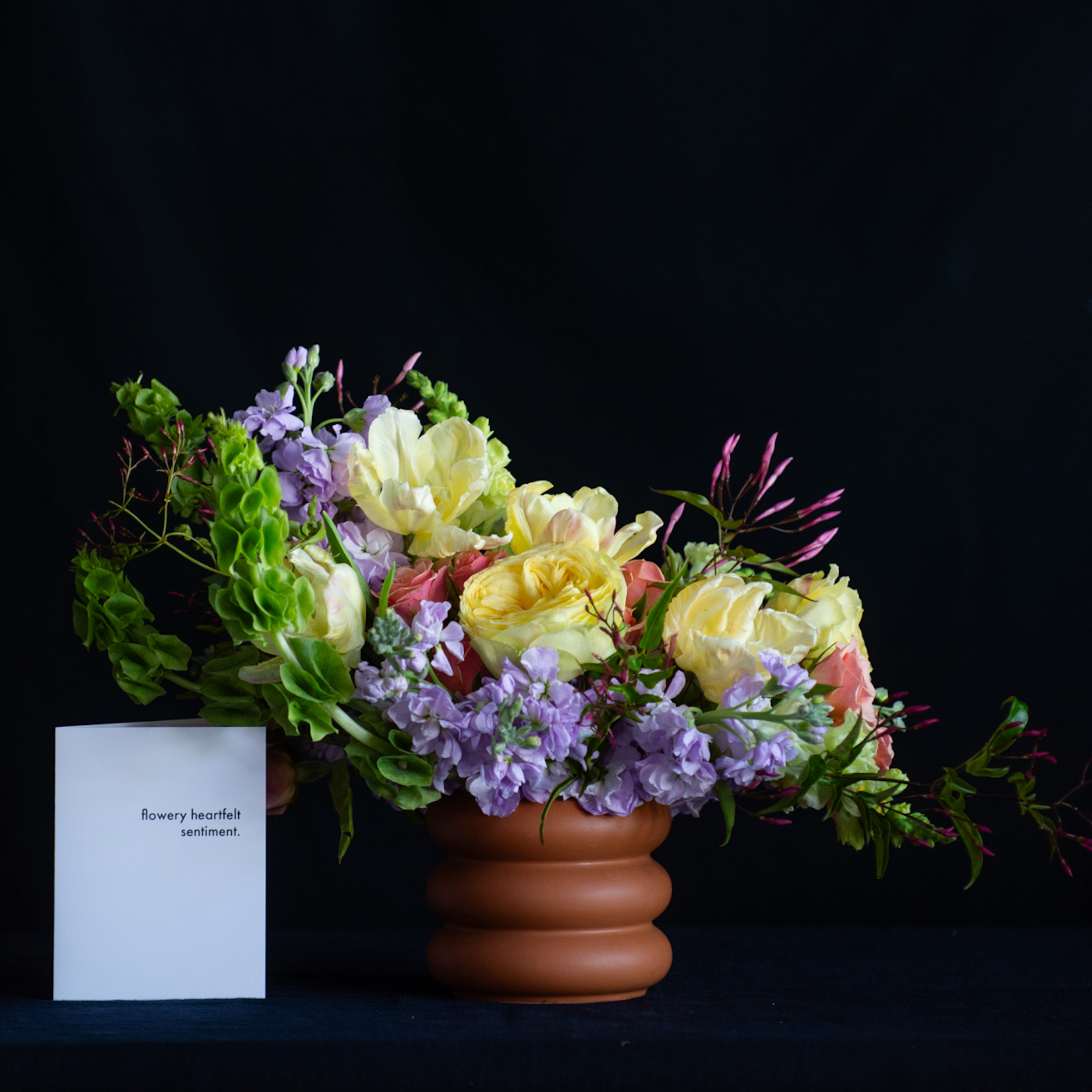 A terracotta stacked vase with pastel garden roses, tulips, and jasmine for Mother's Day