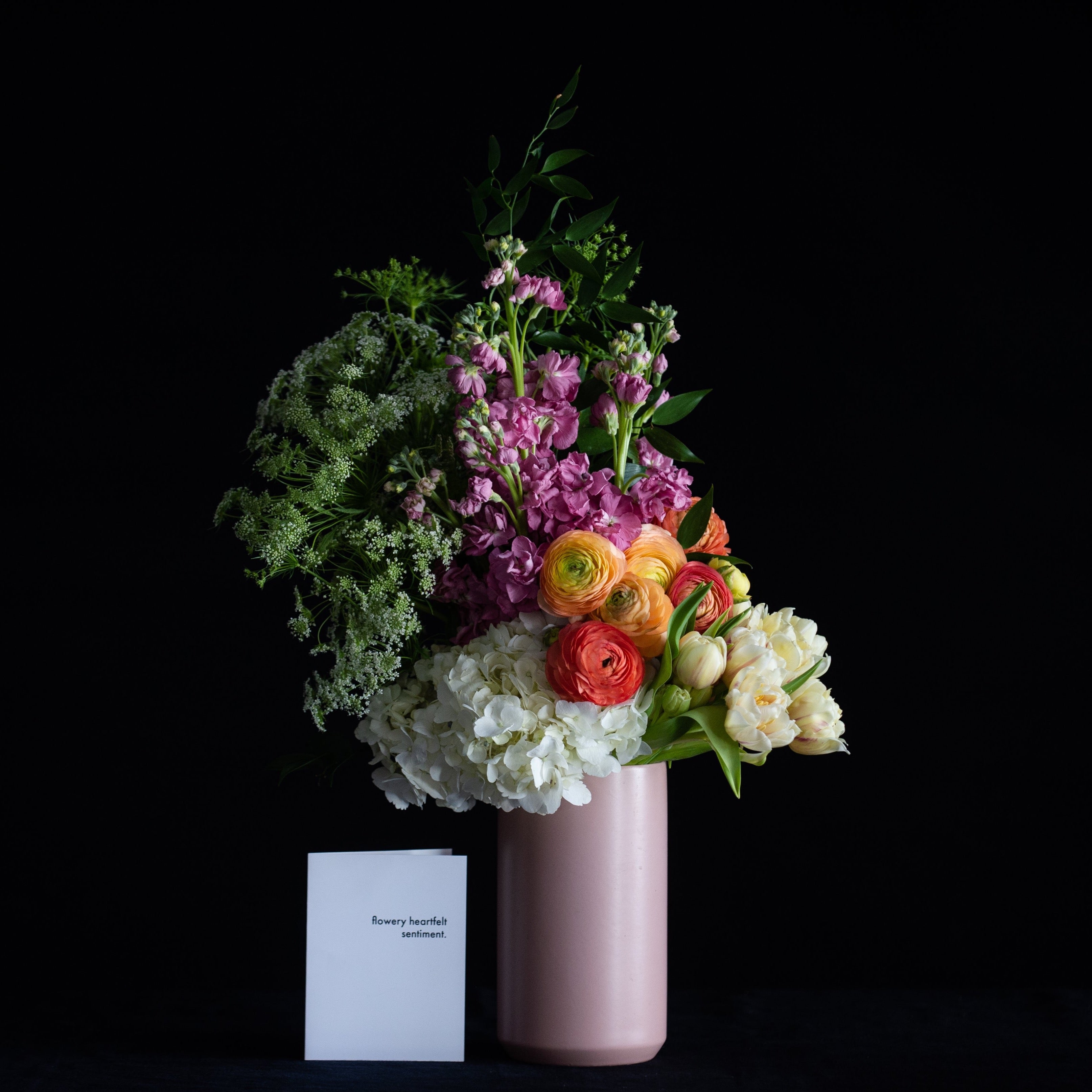 Mother's Day flowers in a pink vase with pastel hydrangea, ranunculus, tulips, and stock. 