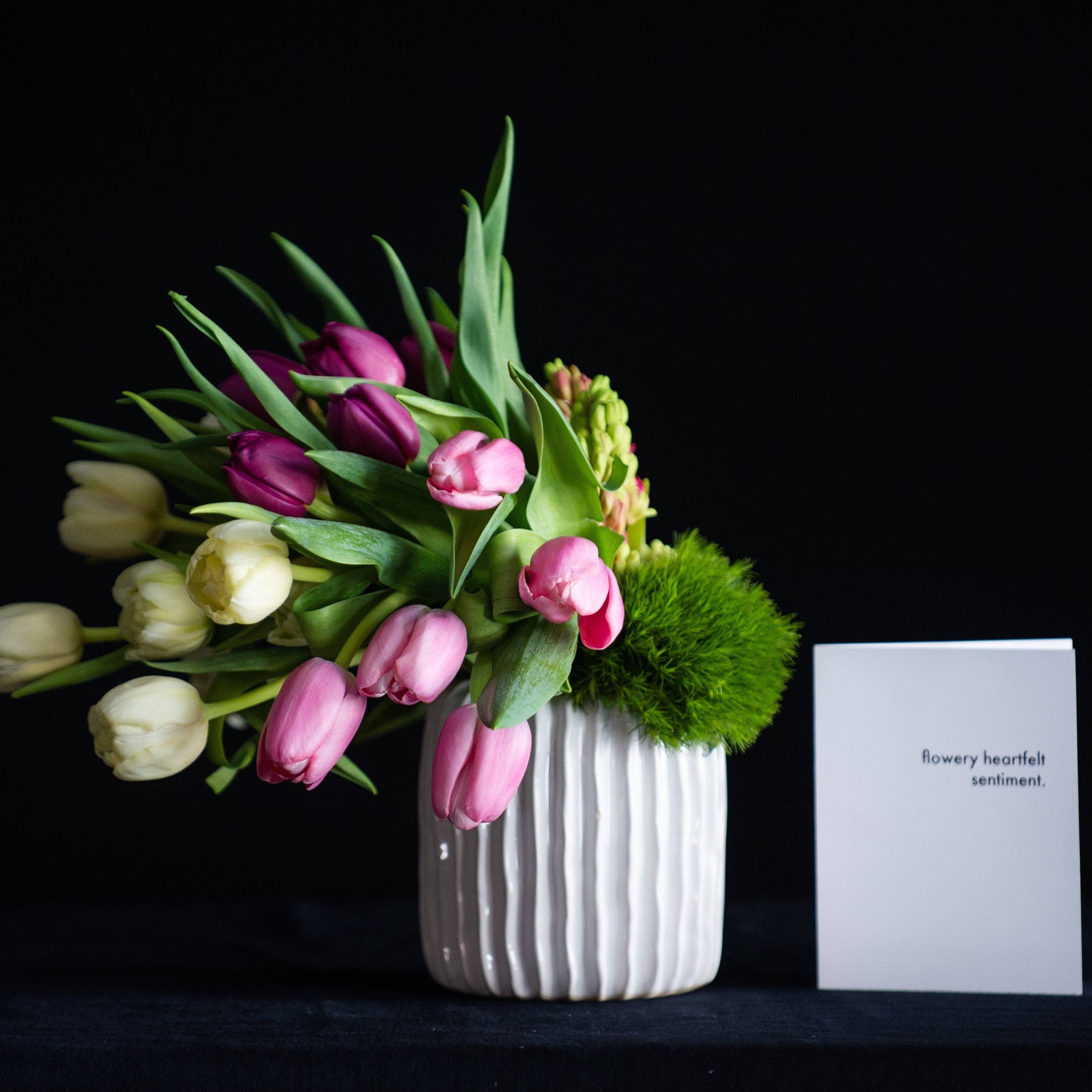 Mother's Day floral arrangement of tulips and hyacinth in pastel colors. In a white ceramic vase