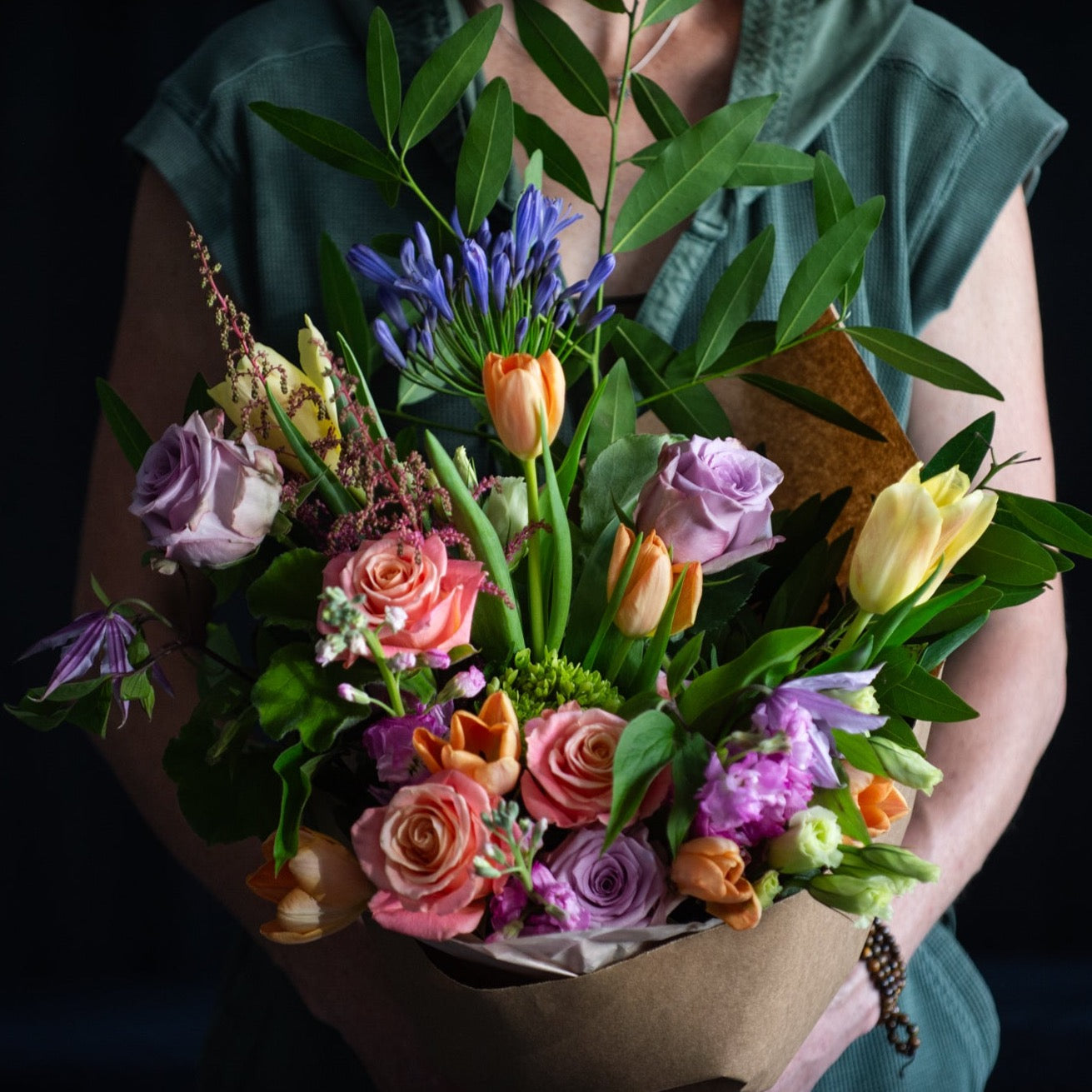 A bouquet of Spring stems for Mother's Day wrapped in Kraft paper. No vase