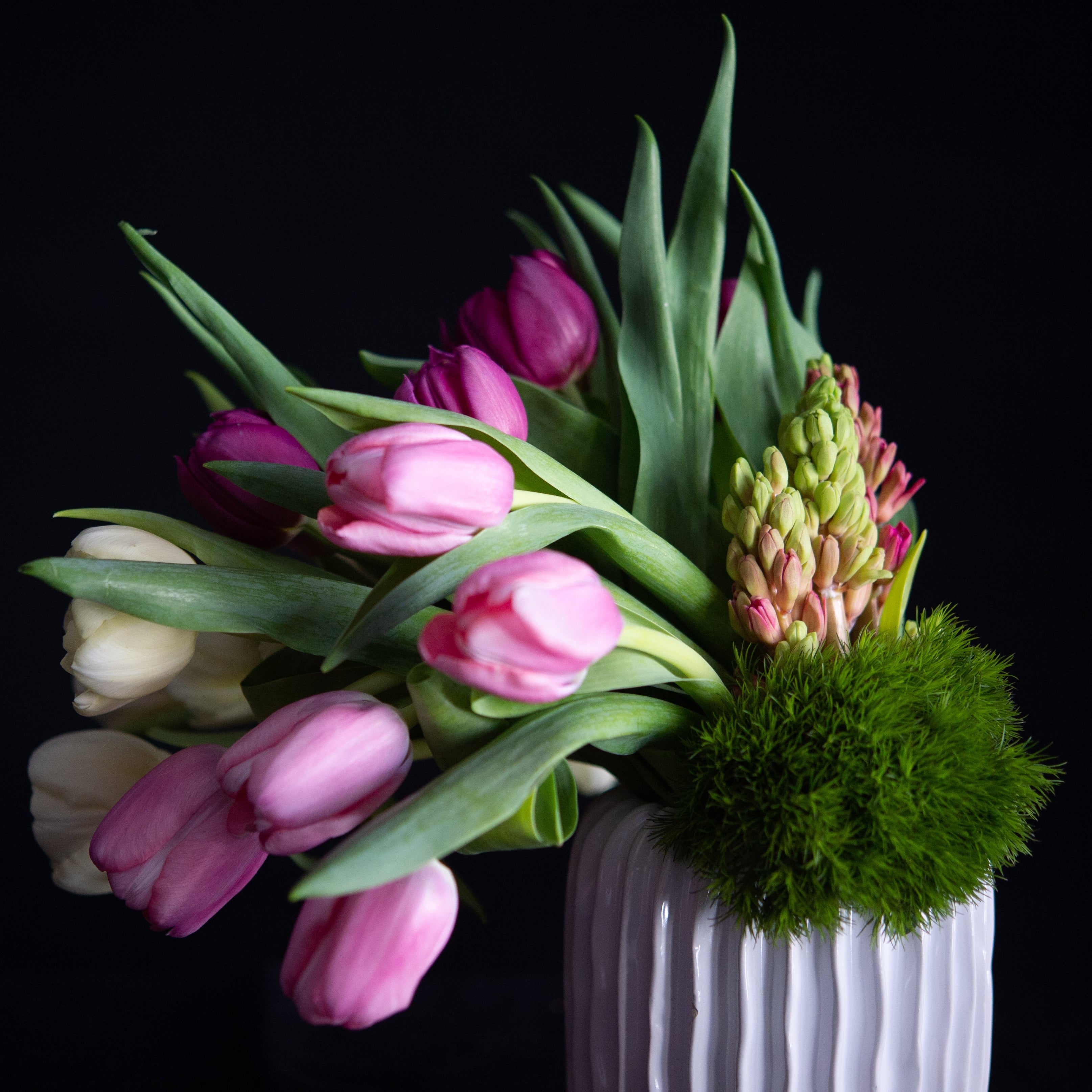 Mother's Day floral arrangement of tulips and hyacinth in pastel colors. In a white ceramic vase