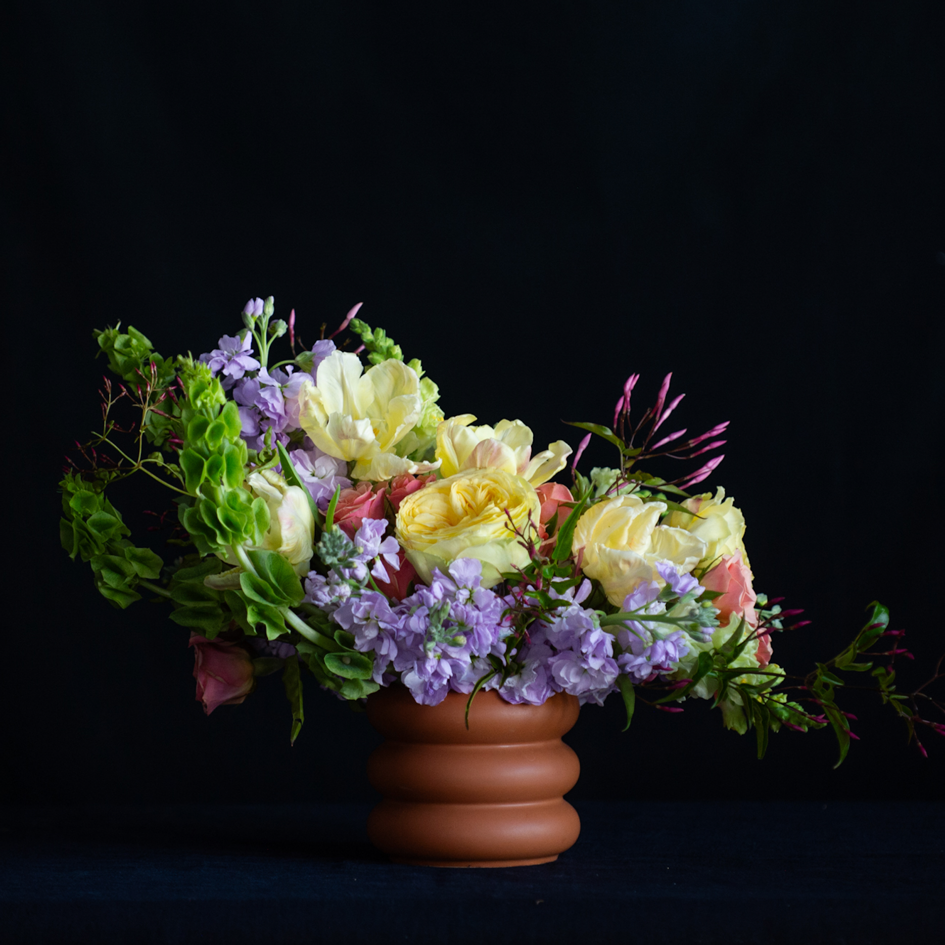 A stacked terracotta pot with pastel stock, garden roses, tulips and jasmine 