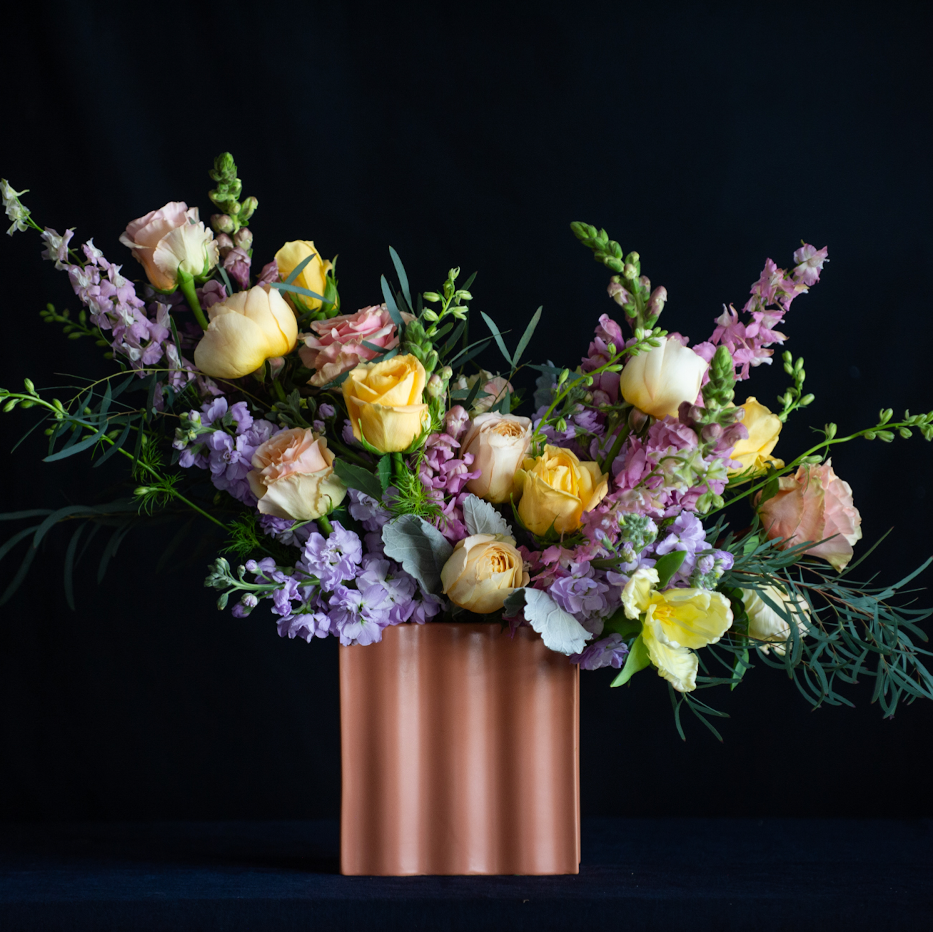A terracotta colored vase with pastel garden roses for Mother's Day