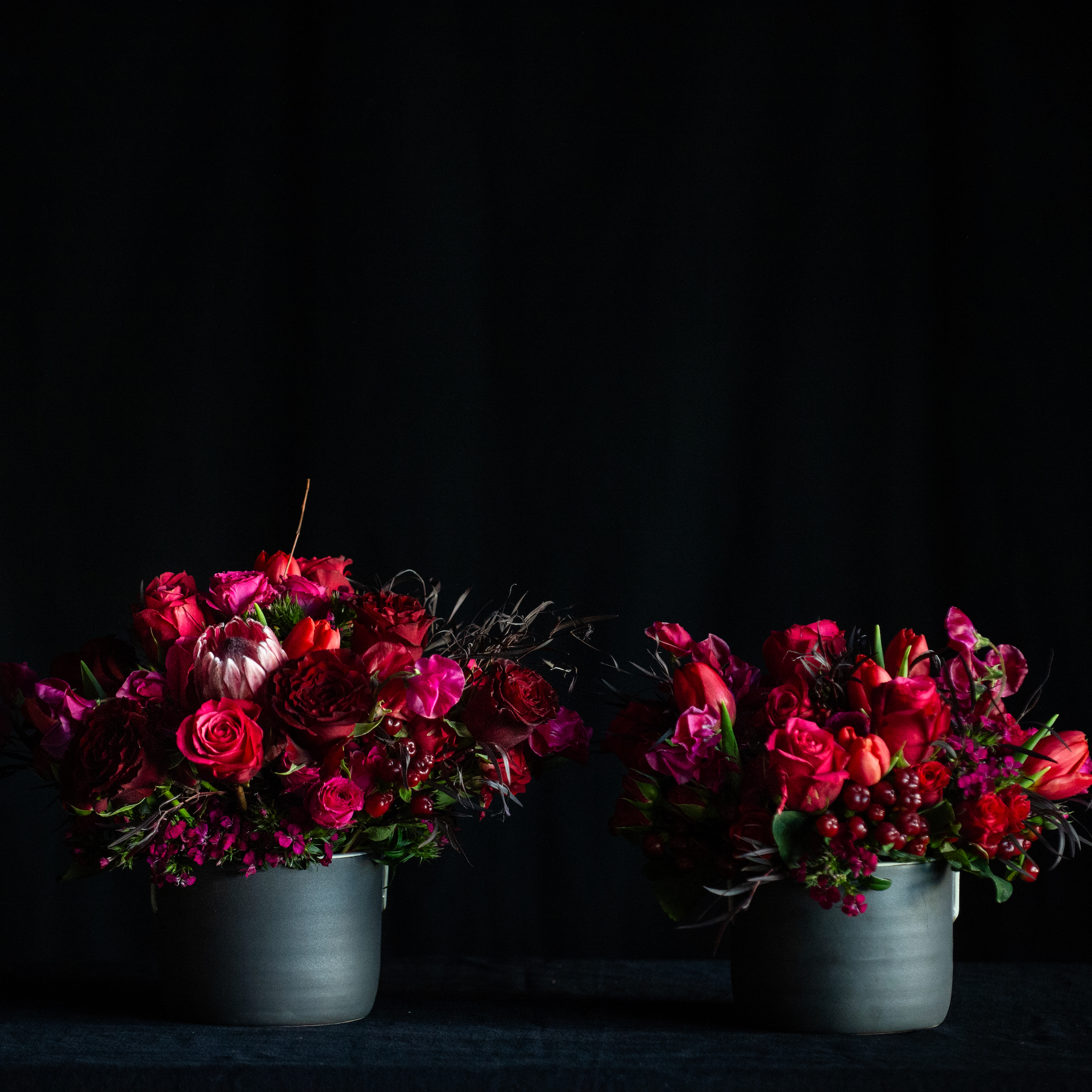 Red roses with chocolate brown foliage in a black container