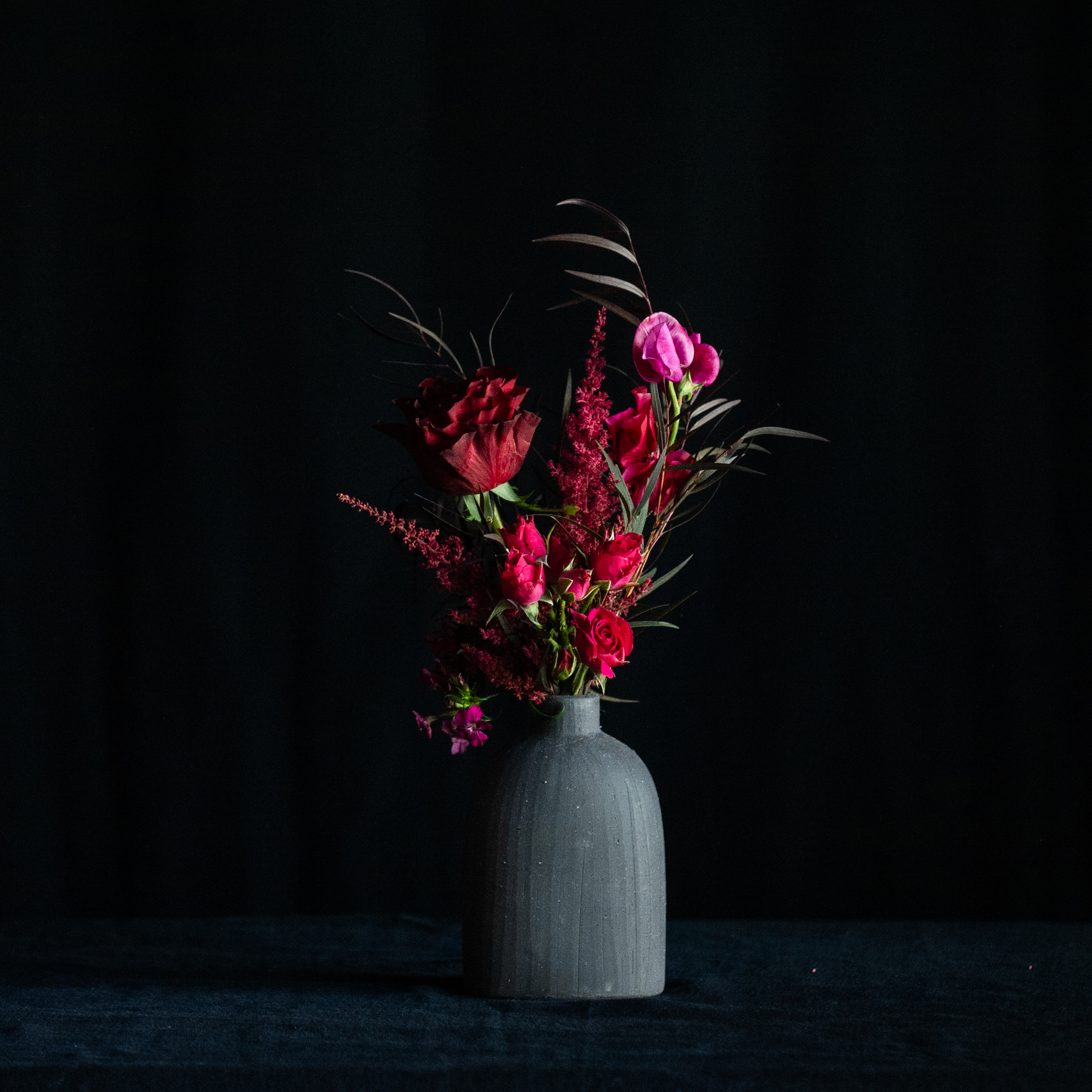 A single red rose with premium accent flowers in a black vase