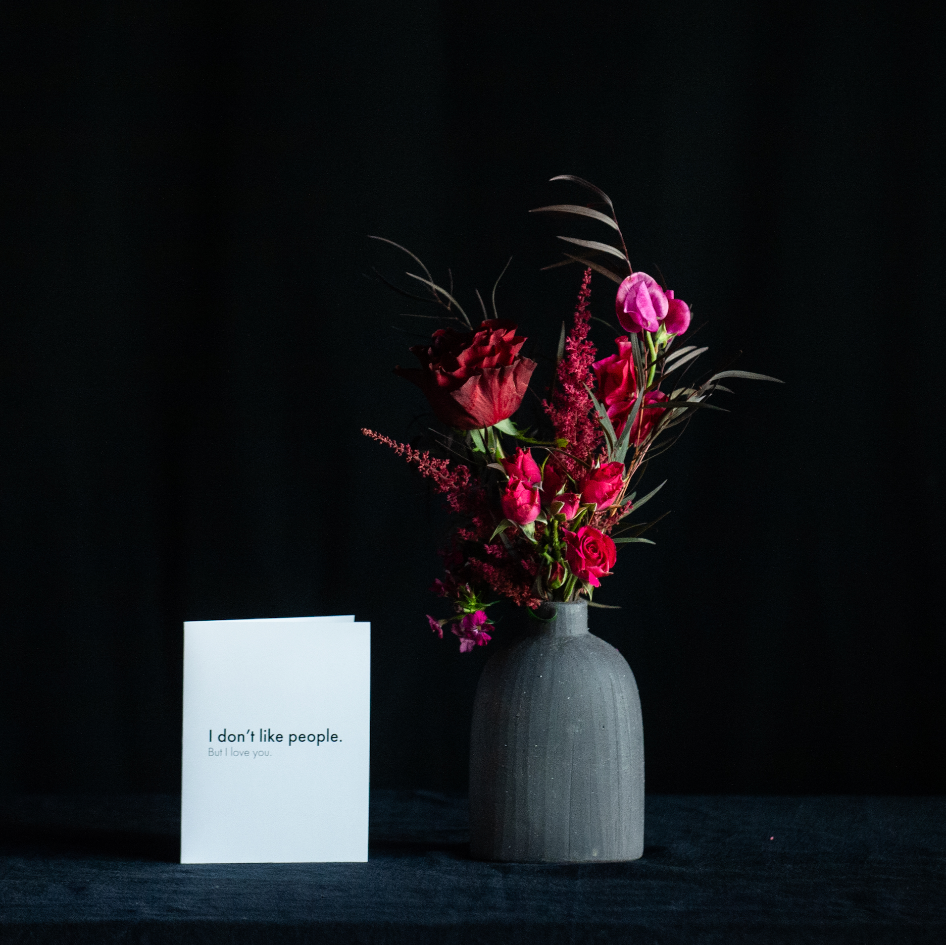 Red rose in black bud vase with premium flower accents