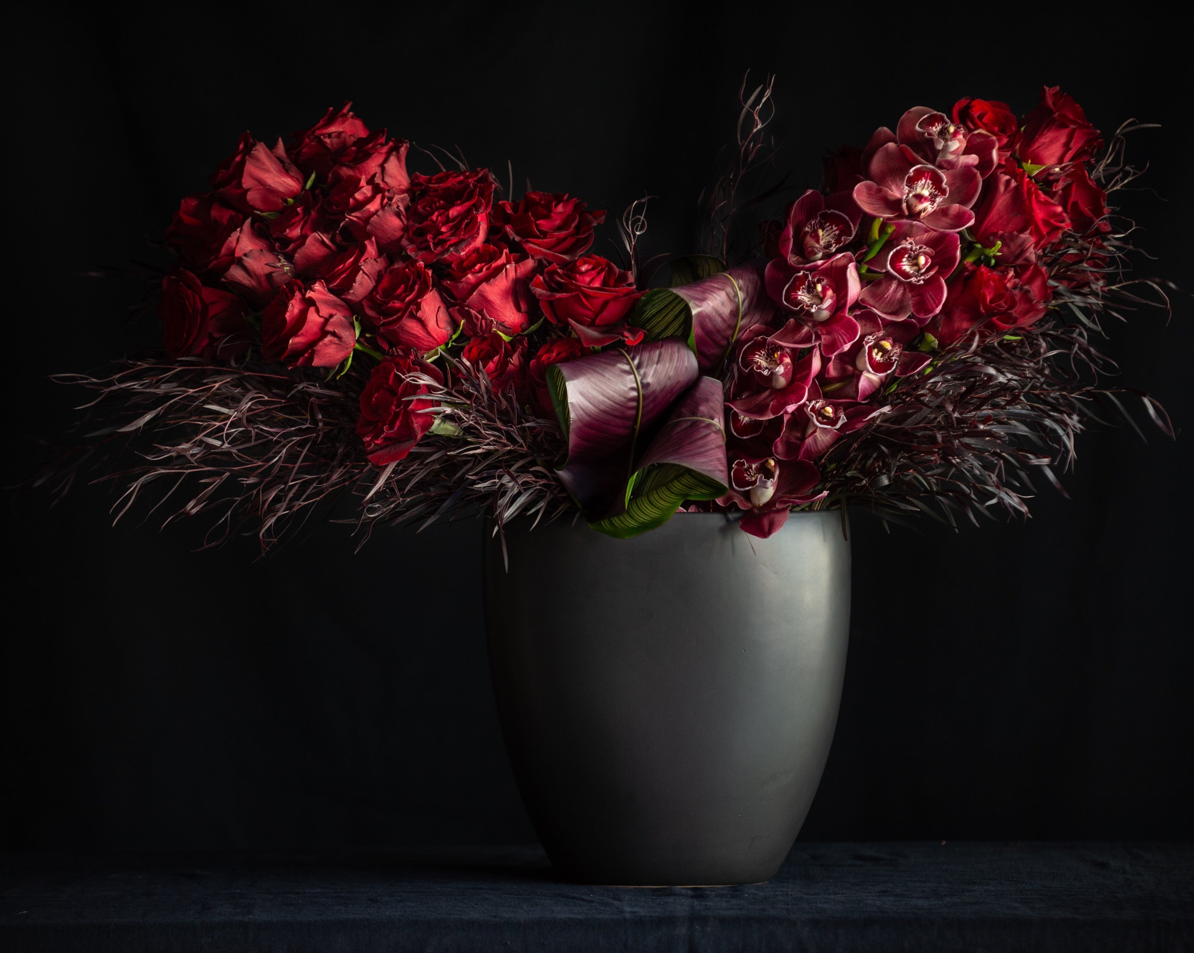 3 dozen red roses with orchids in a black vase for valentines day