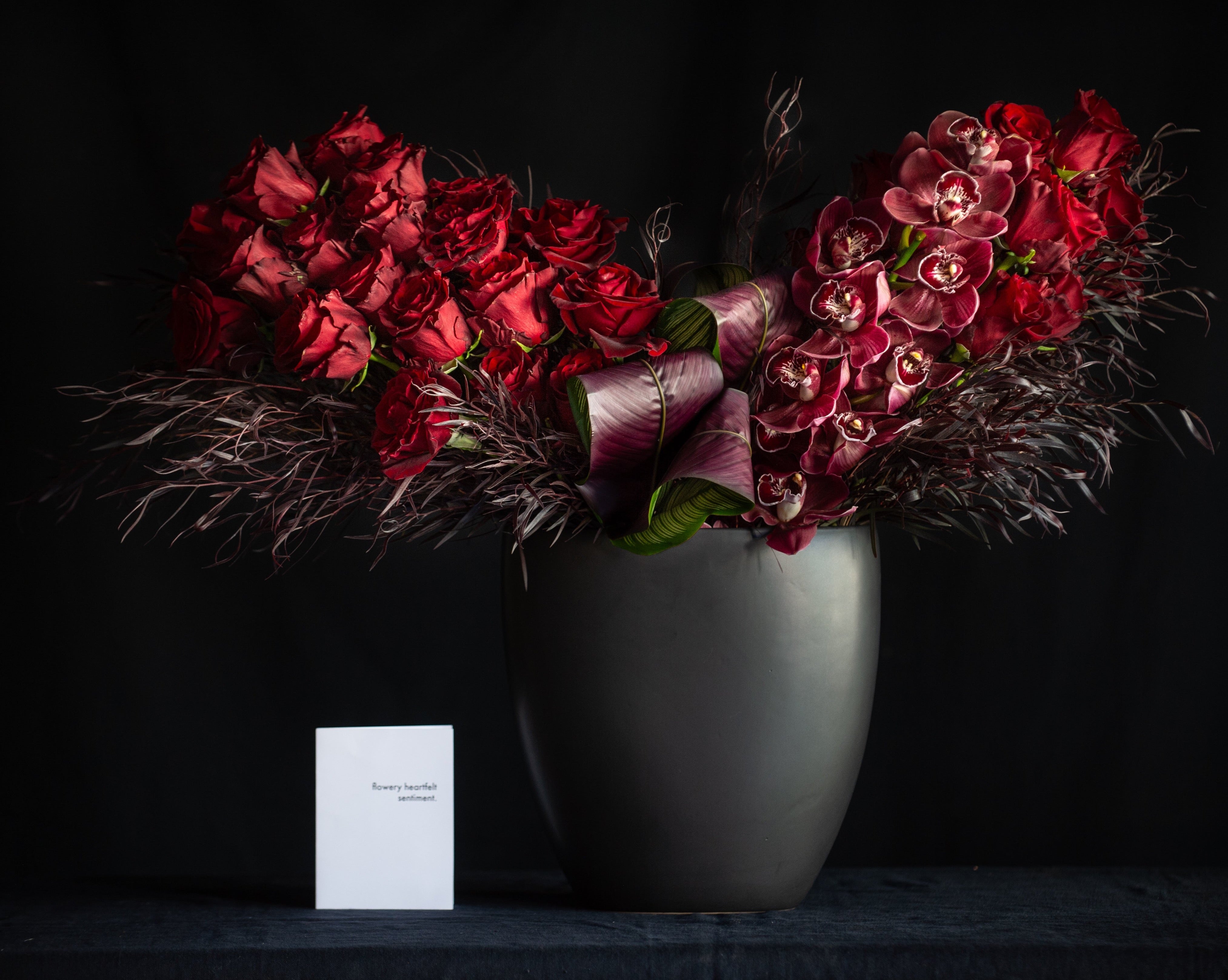 3 dozen red roses with orchids in a black vase for valentines day