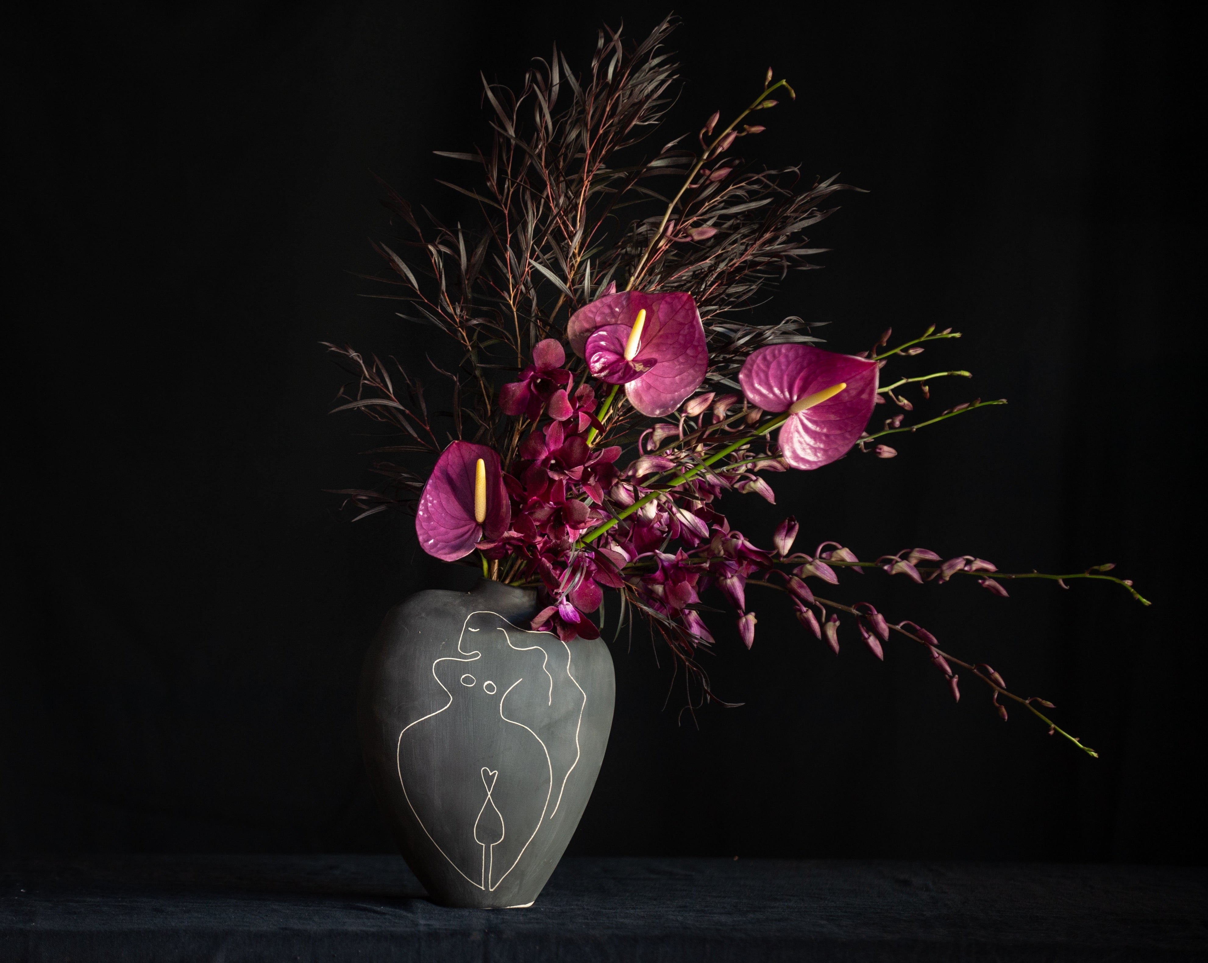 An artistic female vase filled with orchids and anthurium for Valentine's Day