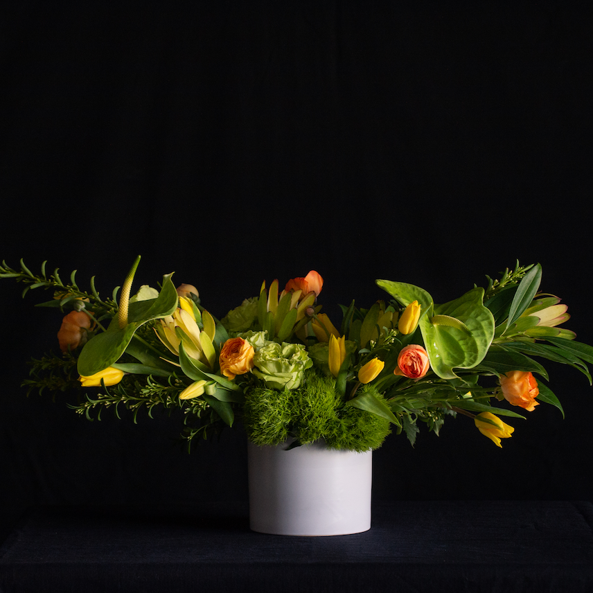 Modern horizontal floral design of green anthurium, green roses, tulips, ranunculus, and premium greenery