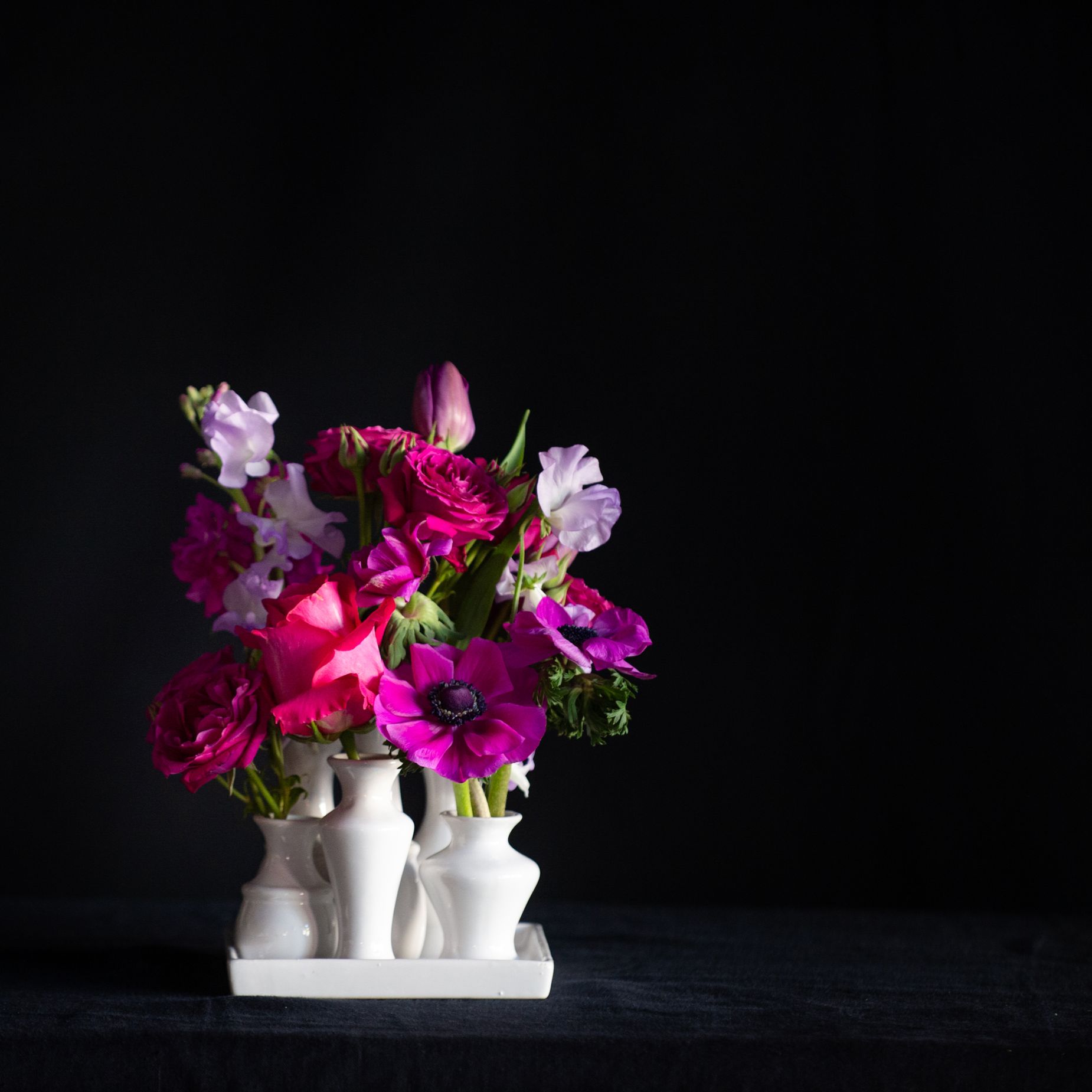 A collection of white ceramic bud vases filled with premium seasonal stems for any day