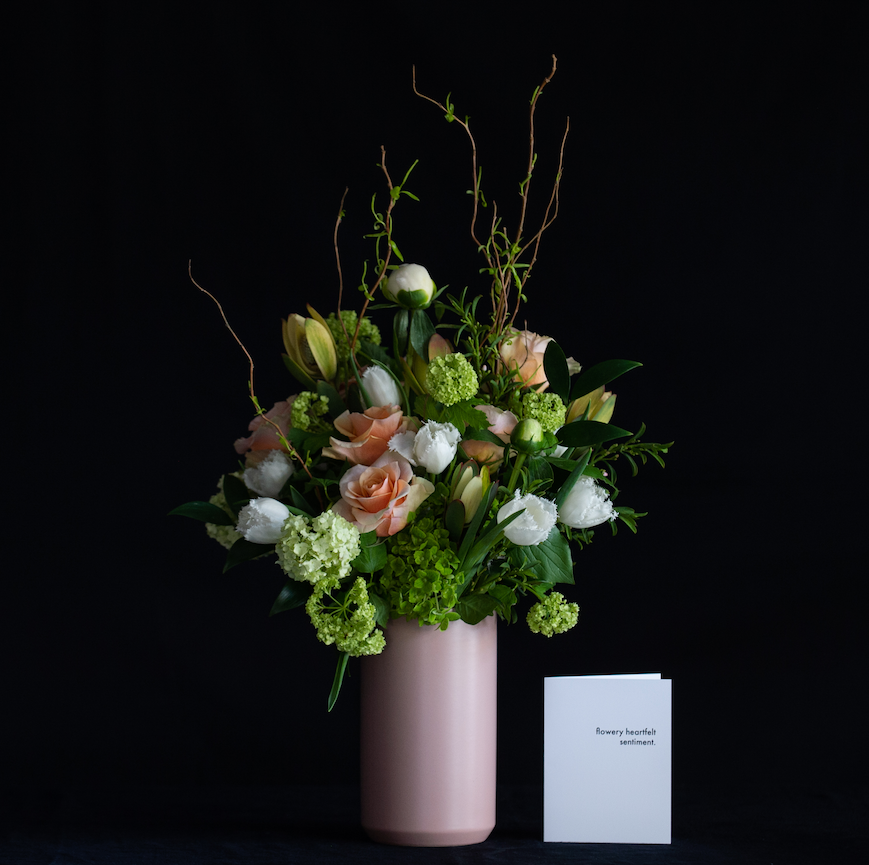 A tall Mother's Day arrangement of peach, white and green stems