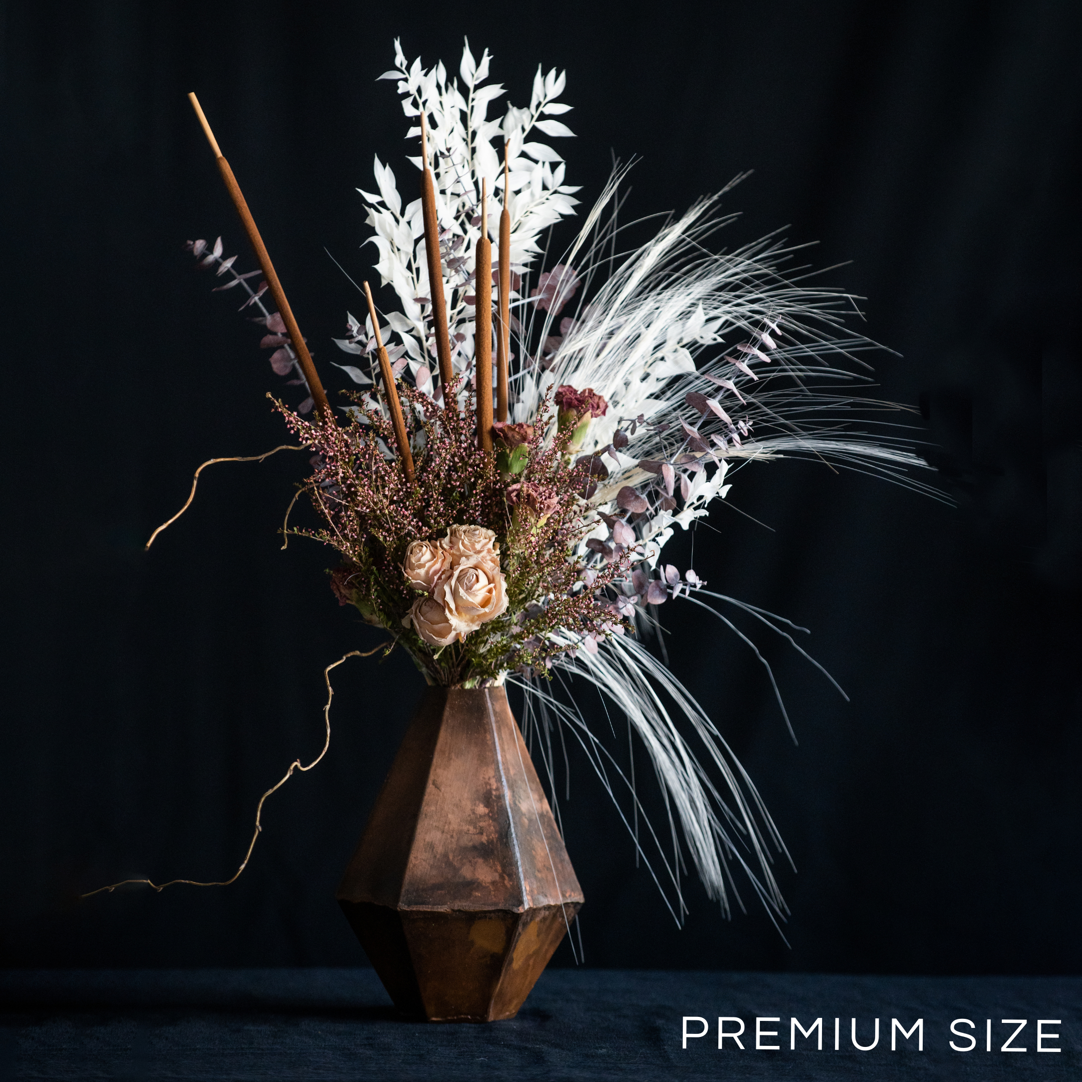 Tall arrangement of dried and preserved flowers in a geometric container