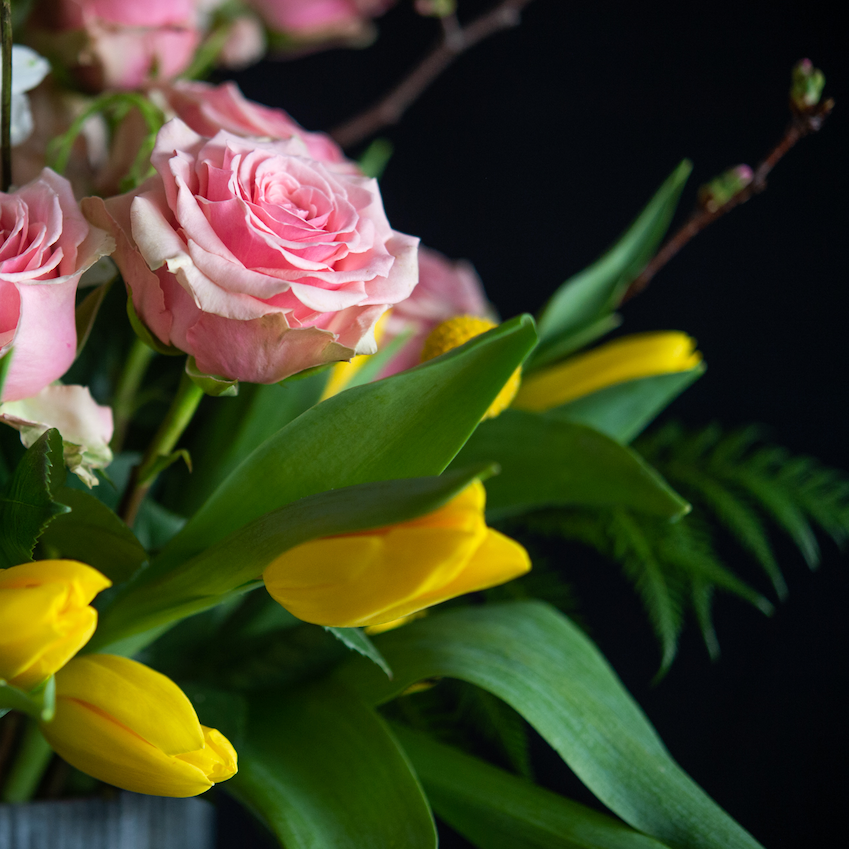 Tall Spring floral design of a dozen roses, tulips, larkspur, stock, and blooming branches. Made by a local florist