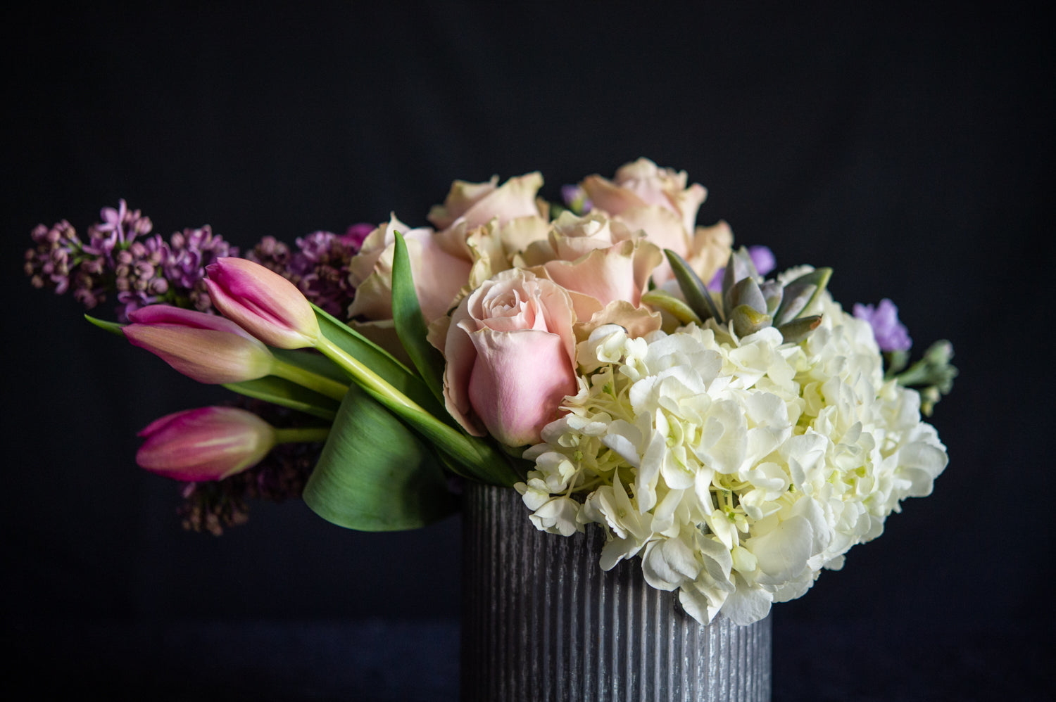Hydrangea, roses, lilac, tulips and a succulent in a zinc container