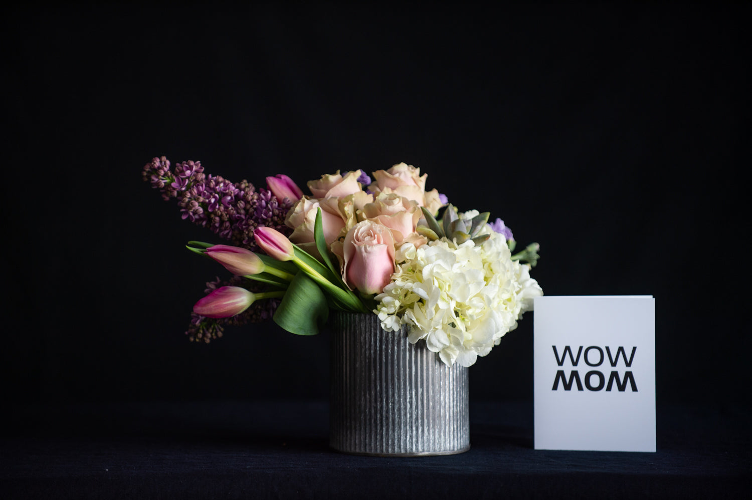 Hydrangea, roses, lilac, tulips and a succulent in a zinc container