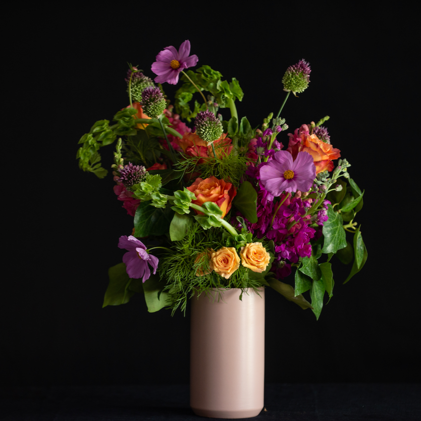 Summer flowers by a local florist - orange roses, magenta stock, premium seasonal stems in a matte pink container