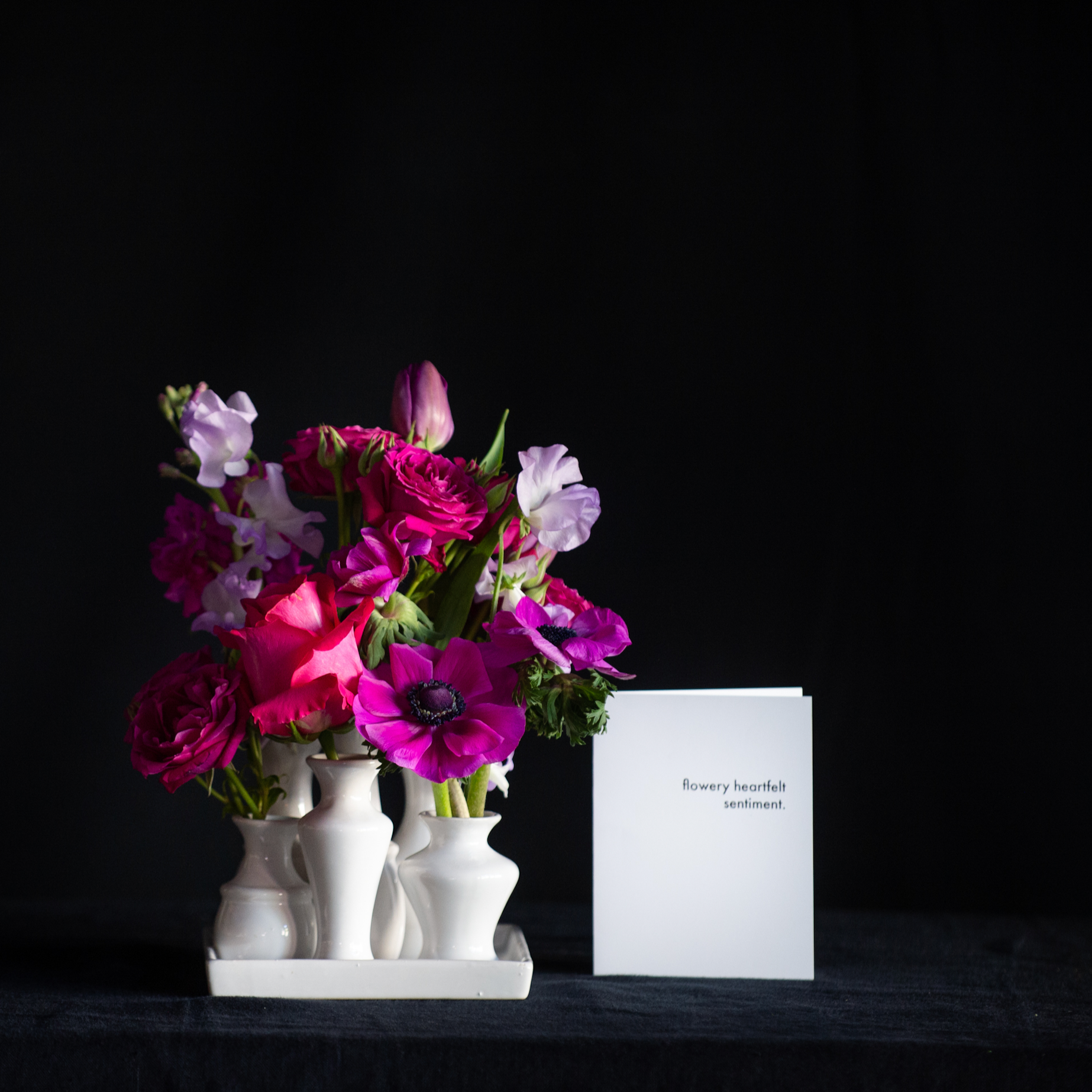 A collection of white ceramic bud vases filled with premium magenta stems for Valentine's Day