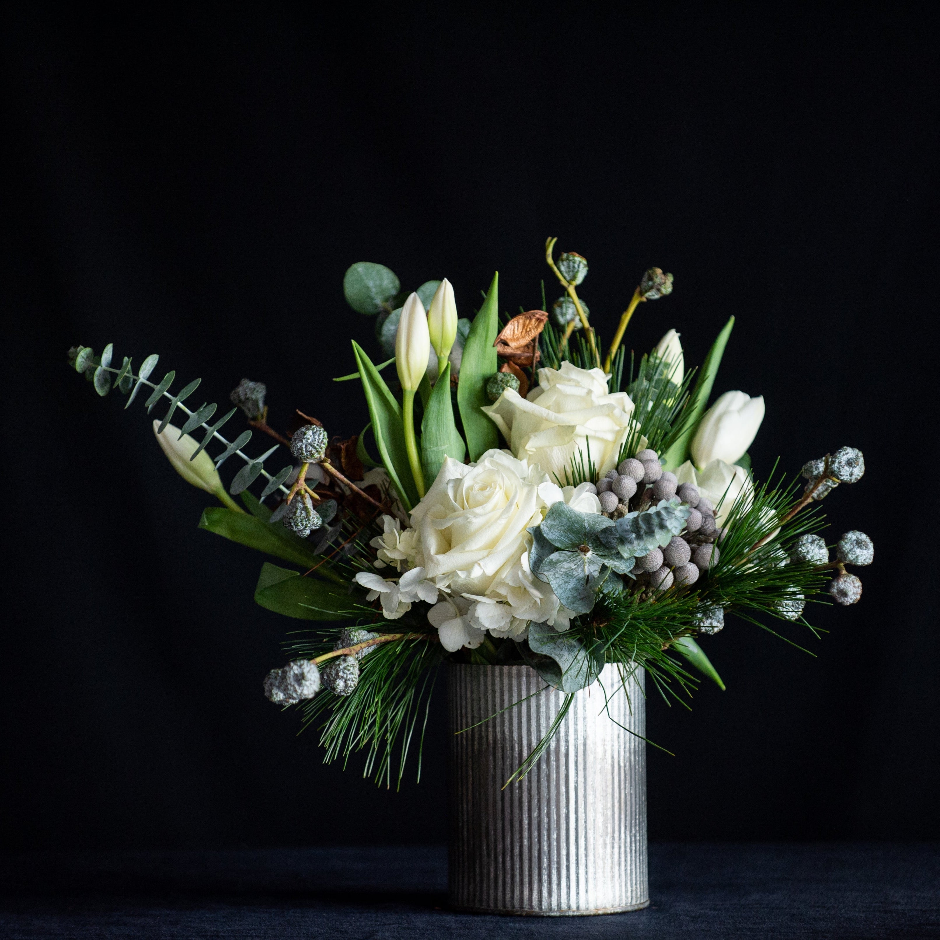  Holiday greens, magnolia leaves, brunia berries, silver bells, and eucalyptus perfectly compliment the creamy winter whites of tulips, roses, hydrangea, and even cotton bolls